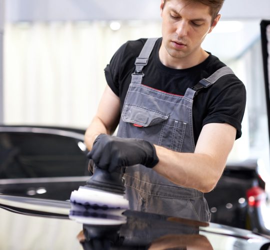 hardworking guy employee in uniform works as car detailer