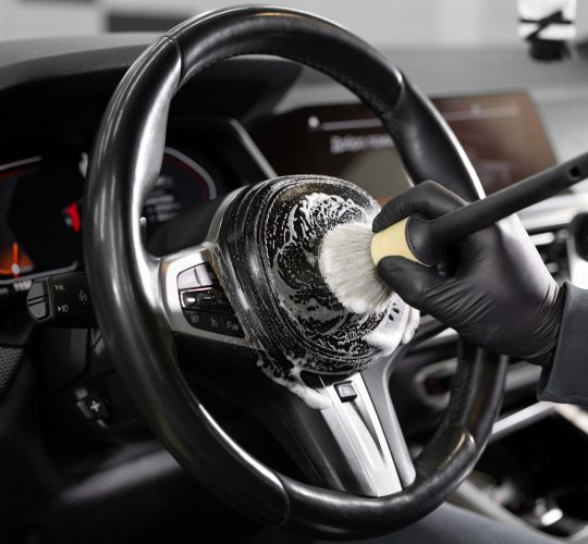 Worker wipes the steering wheel of the car, dry cleaning and interior washing. Detailing studio